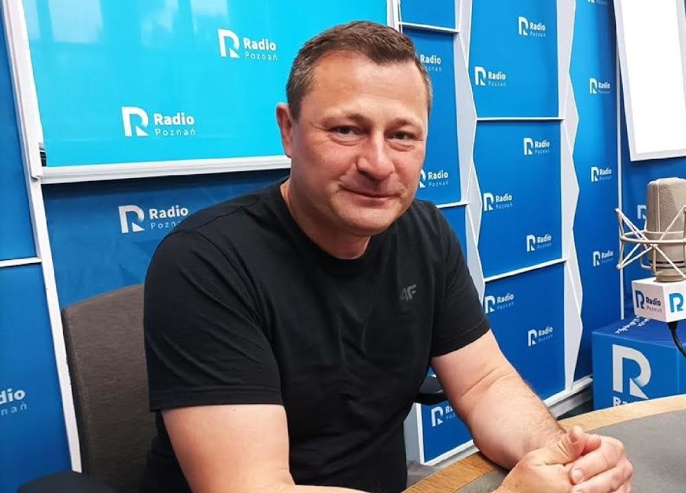 Krzysztof Paszyk w garniturze, w nowoczesnym otoczeniu biurowym.