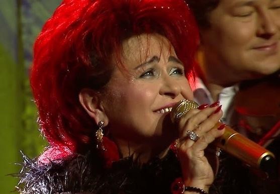 Bernadeta Kowalska śpiewająca na scenie podczas koncertu, w żywym oświetleniu.