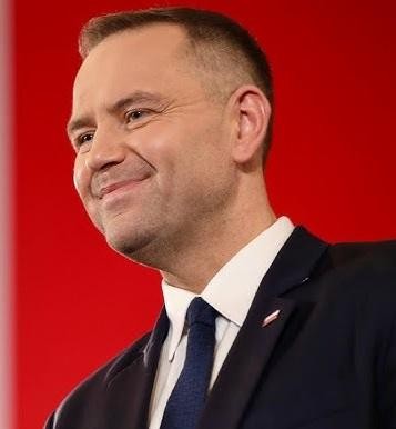 Karol Nawrocki, prezes IPN, na tle ważnego miejsca historycznego w Polsce.