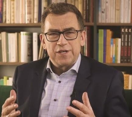 Maciej Orłoś podczas rozmowy w profesjonalnym otoczeniu medialnym.