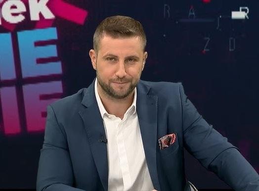 Miłosz Kłeczek prowadzący program publicystyczny w studiu telewizyjnym.
